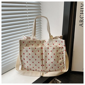 Detail of white corduroy tote bag with red heart pattern and adjustable shoulder straps