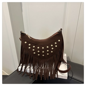 Détail d'un sac demi-lune marron en daim avec des clous dorés et de longues franges
