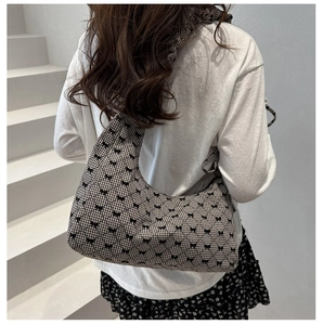 Detail of vintage plaid shoulder bag featuring black bow patterns and elegant crescent design