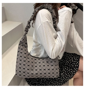 Detail of plaid pleated hobo bag with small black bows and ruffled shoulder strap
