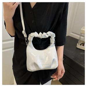 Detail of white glossy bucket bag with ruched cloud handle and adjustable strap