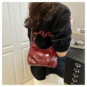 Detail of burgundy patent leather bag showing glossy texture and fashion text print