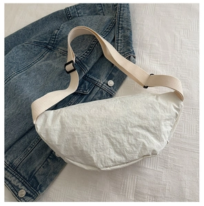 Gros plan du sac banane blanc en nylon avec nœud sur une veste en jean bleu clair