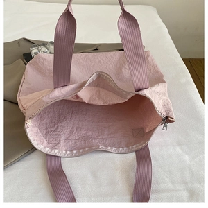 Detail of pink nylon tote bag with silver zipper closure and durable woven handles