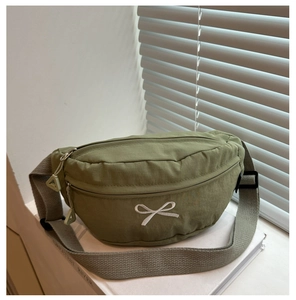 Dettaglio del marsupio in nylon verde con fiocco bianco ricamato e doppia zip resistente