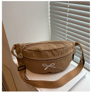 Dettaglio borsa pettorale in nylon kaki con ricamo fiocco bianco e tracolla regolabile