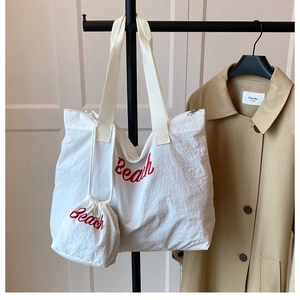 Detail of white nylon tote bag with red Beach text and matching drawstring pouch