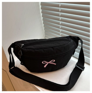 Dettaglio del ricamo farfalla rosa sulla borsa da petto in tela nera con zip