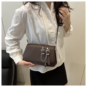 Detail of dark brown leather crossbody bag with silver buckles and chain pendant detail