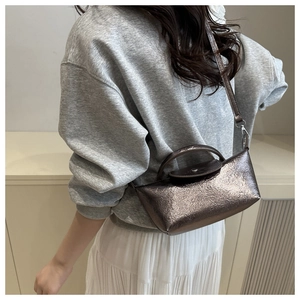 Detail of metallic mini dumpling bag with textured finish and elegant top handle