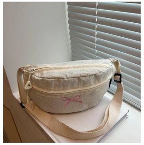 Dettaglio del borsupio in nylon beige con ricamo a fiocco rosa sul davanzale