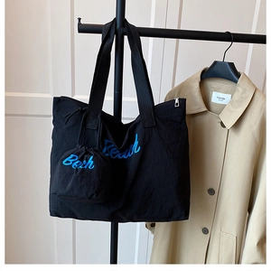 Detail of black nylon tote with blue letter print and matching drawstring pouch
