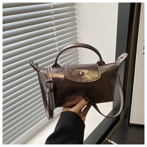 Detail of the metallic faux leather handbag with top handle and round buckle closure