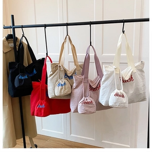 Detail showing five colors of large drawstring beach tote bags with matching mini pouches