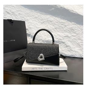 Detail of black sequined flap handbag with silver heart-shaped twist lock and top handle