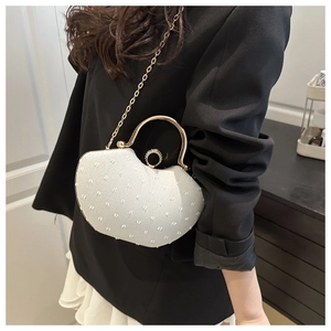 Detail of white pearl evening shell bag with gold metal handle and chain strap
