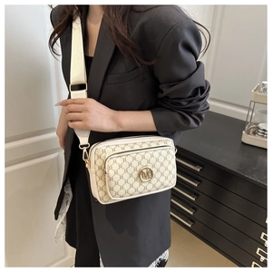 Detail of retro letter print crossbody bag with golden M logo and wide strap on model