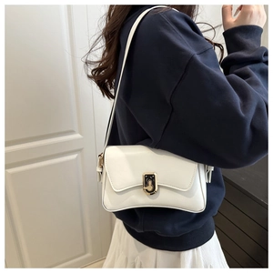 Detail of elegant white leather shoulder bag with chic black-gold square rotary metal lock