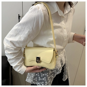 Close-up of cream yellow crossbody bag with silver buckle worn by a female model