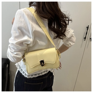 Détail d'un sac sous le bras en cuir crème avec un fermoir doré et une bandoulière chic