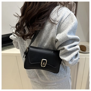 Detail of a black matte faux leather crossbody bag with gold metallic twist lock on model