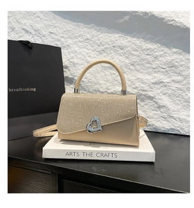 Detail of beige shoulder bag featuring sparkling rhinestone flap and silver heart clasp