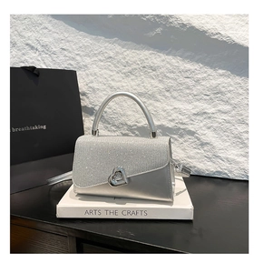 Detail of silver square handbag featuring heart metal clasp and sparkling glitter finish