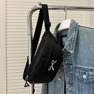 Détail du sac bandoulière en nylon noir avec broderie ruban rose et sangle ajustable