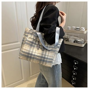 Detail of tartan tote bag featuring blue woven handles and decorative grey knots