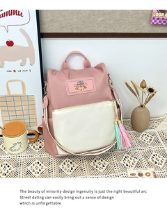 Détail du sac à dos en nylon rose et crème avec oreilles de lapin et pampilles colorées