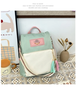 Détail du sac à dos bicolore avec nylon vert, étiquette rose et bretelles rayées