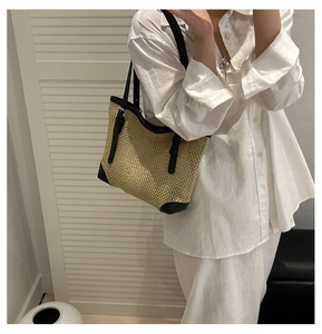 Detailed view of handmade woven straw tote bag with black leather trim and long handles