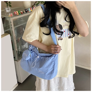 Close-up of light blue waterproof nylon shoulder bag with fashion embroidery and wide strap