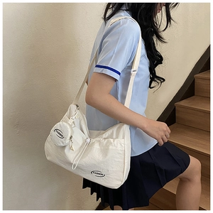 Detail of white canvas crossbody bag featuring pleated drawstring and round coin pouch