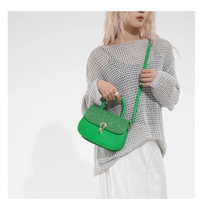 Détail du sac vert en cuir avec rabat scintillant et fermoir en U métallique doré