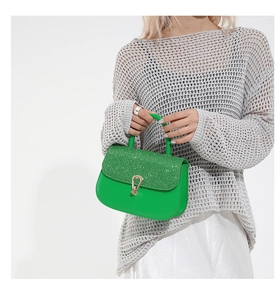 Détail d'un sac à main en cuir vert vif avec rabat orné de cristaux et fermoir doré