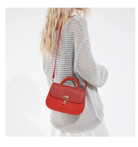 Détail du sac rouge avec texture pailletée, fermoir doré et fine bandoulière réglable