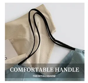 Detail showing the light blue corduroy fabric texture and black shoulder strap attachment
