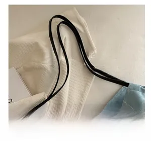 Detail showing the light blue corduroy fabric texture and black shoulder strap attachment