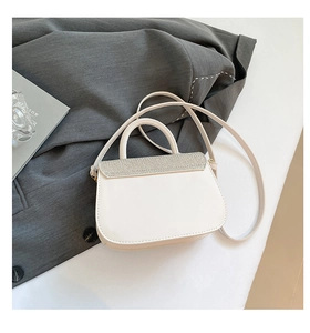 Détail du sac à bandoulière blanc orné de strass argentés brillants sur le rabat