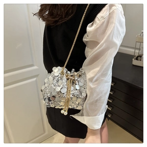 Detail of silver sequin bucket bag with gold chain strap and pearl drawstring accents