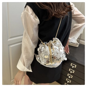 Detail of silver sequin bucket bag with gold chain strap and pearl drawstring tassels