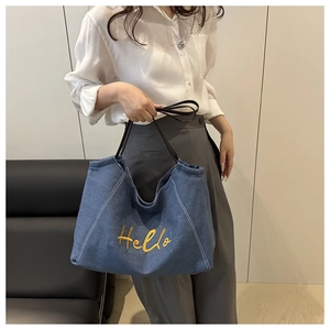 Sac fourre-tout en denim bleu avec broderie Hello jaune porté par un mannequin de profil