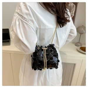 Detail of black sequined bucket bag with golden chain strap and pearl drawstring accents
