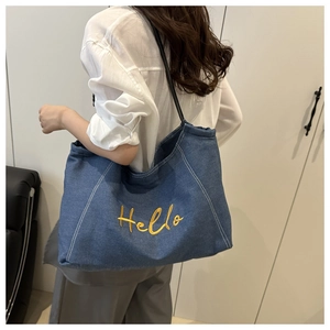 Detail of blue denim tote bag with Hello embroidery and white contrast stitching