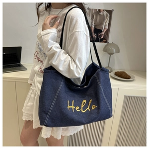Détail du sac cabas en jean bleu avec broderie Hello jaune et anses noires élégantes