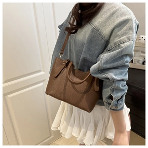 Detail of dark brown lychee grain leather bucket bag styled with casual denim outfit