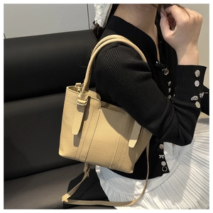 Detail of light brown lychee grain leather crossbody bucket bag with gold hardware