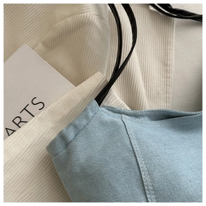 Détail d'un sac à main en denim bleu clair avec coutures blanches contrastées et sangle noire