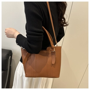 Detail of caramel lychee grain leather tote bag with elegant metal rings and top handles
